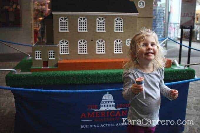 Toddler eating Johnny Rocket's ice cream in front of Lego Americana exhibit